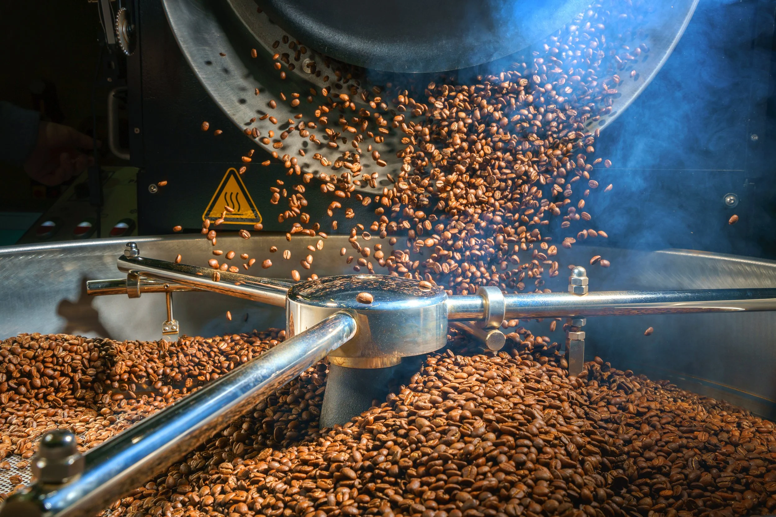 A Plaid Coffee small-batch roaster pouring hot beans into the cooling tray