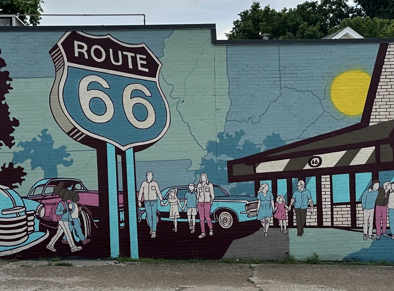 Detail of the Plaid Coffee Route 66 mural: the Route 66 shield, an Illinois state map, families walking, and a painted diner with a bright sun